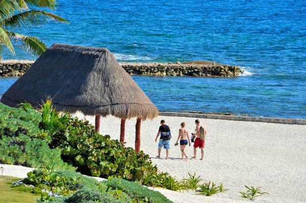 Friends Walking Alongside Thatched Palapa at Riviera Maya, Mexico - Encircle Photos