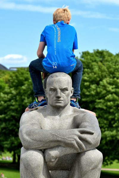 Boy Sitting Backwards on Granite Sculpture at Frogner Park in Oslo, Norway - Encircle Photos