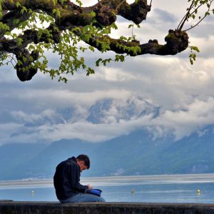 Man Sitting with Lake Geneva and Alps in Ouchy, Switzerland - Encircle Photos