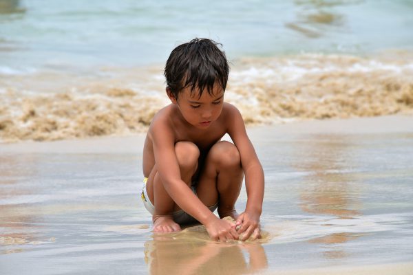 Boy Playing in Sand and Surf on Patong Beach in Phuket, Thailand - Encircle Photos